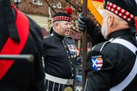 one man in background dressed in formal uniform with badges on his chest, one man blurred in foreground looking the opposite direction
