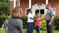 A handshake opens a conversation between an APD officer and a young community member outside Alexandria Free Methodist Church.