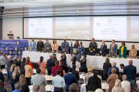 Attendees and head table guests stand as the APD honor guard presents the colors and a young singer holds a microphone at the lectern during the inaugural Faith & Blue Prayer Breakfast.