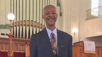 man smiling in suit with church in background