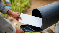 person taking letter out of black mailbox