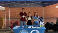 tree city employees standing under a blue tent with swag outdoors 