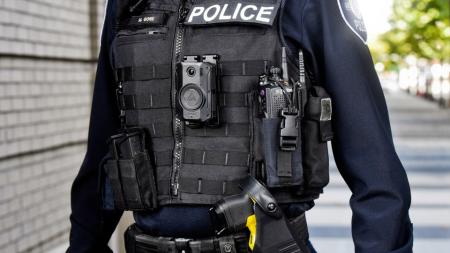 An unidentifiable officer, with a police radio and body worn camera.