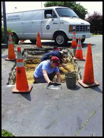 digging test pit in parking lot protected by orange cones 