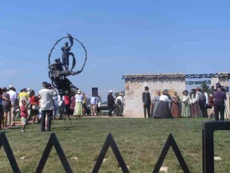 Group of people gathered by statue and monument, including Washington Revels Jubilee Voices performers in costume