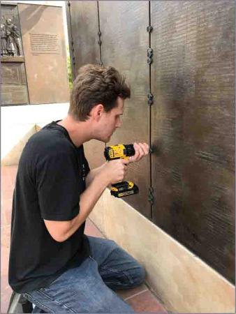 man with drill at bronze plaque