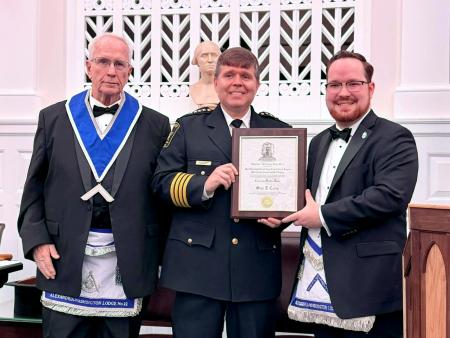 Two men in wearing Masonic regalia presenting an award plaque to Sheriff standing in the middle.