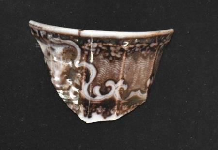 Part of a whiteware teacup with a floral decoration