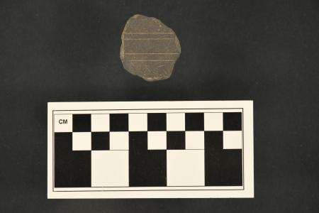 An approximately 4 cm fragment of a slate tablet, with two sets of inscribed parallel lines