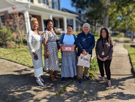 Five people standing in front of a single-family home with a white porch. L to R: Belinda Fadlelmola, Tiffany Freeman, Kim Cadena, Eric Keeler and Shaina Gaines.