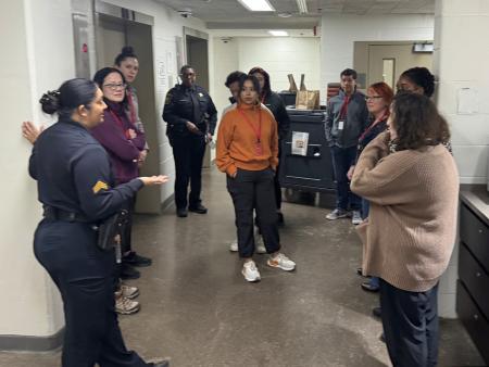 Sheriff's sergeant in a blue uniform giving a tour of the jail to several civilians