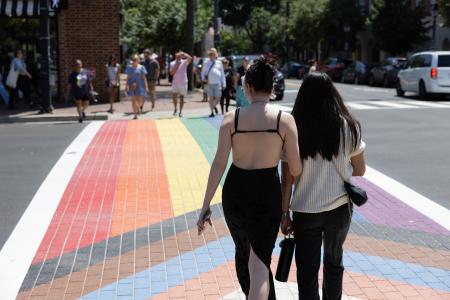 Couple walking across rainbow crosswalk