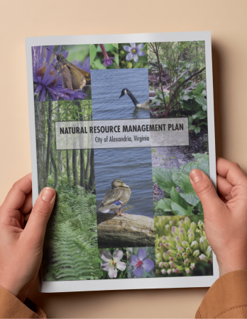 Two hands with brown sleeves holding a booklet with images of nature in Alexandria with the words Natural Resource Management Plan City of Alexandria, Virginia