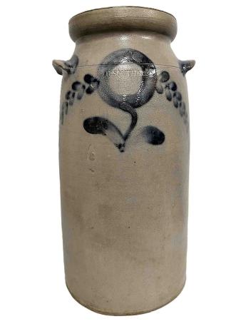 This tall cylindrical grey salt-glazed stoneware vessel was used to churn butter. It is stamped H. SMITH & CO. and decorated with a brushed cobalt blue round flower on a curved stem with curving branches of leaves.