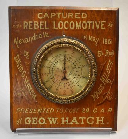 This steam gauge, taken as a souvenir, is mounted on a board lettered in gold on red, “CAPTURED REBEL LOCOMOTIVE/Alexandria Va. In May 1961 by David G. Hatch 5th Regt Mass Militia/Presented to Post 29 G.A.R. by GEO. W. HATCH”