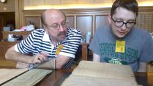 Two researchers look over documents held in an archive.