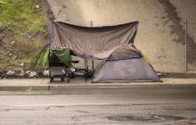 A homeless encampment under a bridge during a rain storm