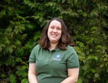 Image of Katrina Napora Natural Resources Manager wearing a green shirt in a background of trees