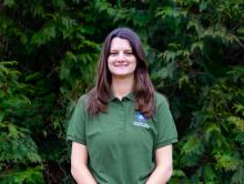 Image of Raychel Frye Natural Resources Manager wearing a green shirt in a background of trees