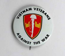 This button reads “Vietnam Veterans against the War” around a red and gold shield with a rifle and helmet.