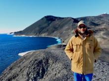 Man with a beige jacket with views to a cliff